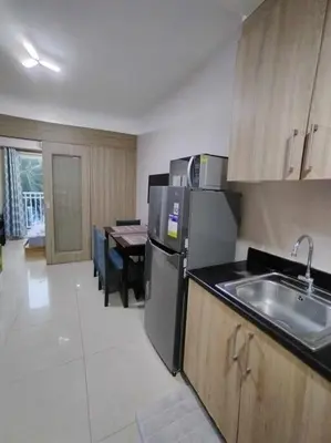 a kitchen with a refrigerator and a sink and a table at Near MOA at SHORE RESIDENCES 1BR with balcony -unlimited WIFI in Manila