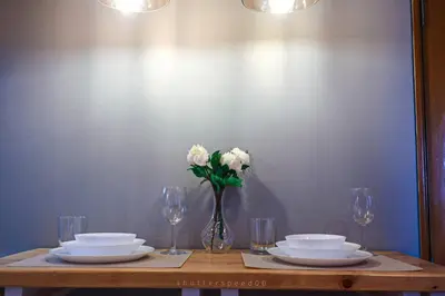 a table with plates and a vase with white flowers at Best Deal! Cozy and Minimalist 2BR nr Airport in Manila