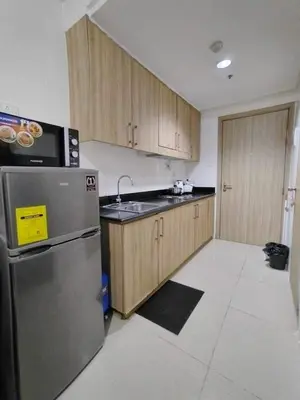 a kitchen with wooden cabinets and a stainless steel refrigerator at Shore 1 Residences - 1 Bedroom with Balcony in Manila