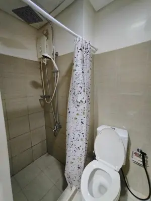 a bathroom with a shower with a toilet and a shower curtain at Shore 1 Residences - 1 Bedroom with Balcony in Manila