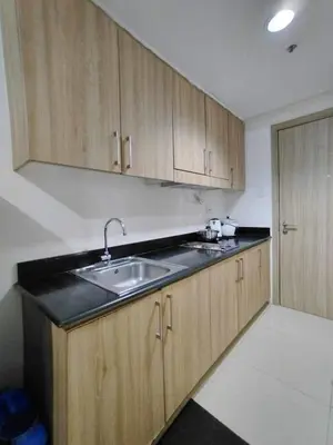 a kitchen with a sink and wooden cabinets at Shore 1 Residences - 1 Bedroom with Balcony in Manila