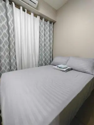 a bedroom with a large white bed with curtains at Shore Residences - 1 Bedroom with Balcony in Manila