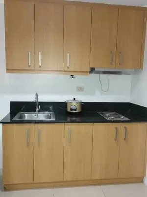 a kitchen with a sink and wooden cabinets at spacious 1 br fully furnished condo in Manila