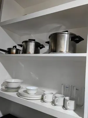 a shelf with pots and pans and plates in a kitchen at VM Staycation Grace Residence Taguig in Manila