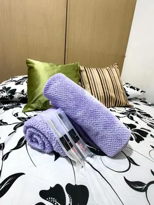 a pair of purple mitts sitting on a bed at VM Staycation Grace Residence Taguig in Manila