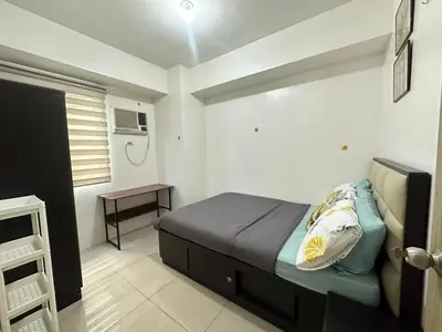 a bedroom with a bed and a table in it at 2br shore residences staycation in Manila