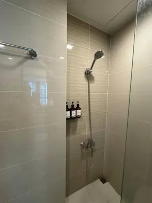 a shower with a glass door in a bathroom at One Uptown Stylish Retro Suite in Manila