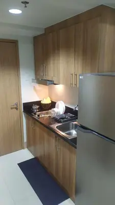 a kitchen with wooden cabinets and a sink and a refrigerator at Casa Laelia in Manila