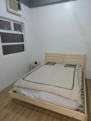 a bed in a room with a white wall at 1 Bedroom Apartment in Central Makati in Manila