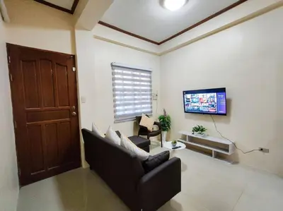 a living room with a couch and a flat screen tv at Spacious Apartment near Evia Daang Hari in Manila