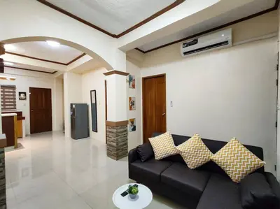 a living room with a black couch and a kitchen at Spacious Apartment near Evia Daang Hari in Manila
