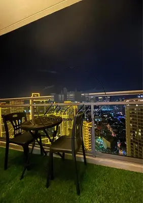 a table and chairs on a balcony at night at MetroNest Dettifoss in Manila