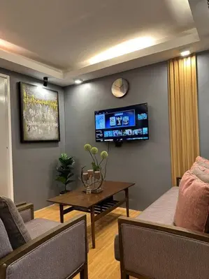a living room with a table and a tv on the wall at H&D Suites-Memories are personal in Imus