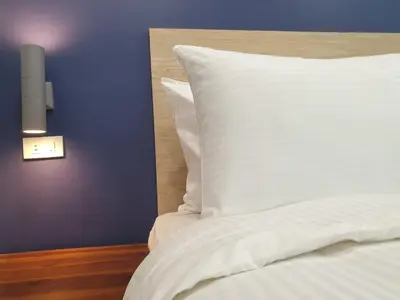 a bed with a white pillow and a blue wall at Leez Inn Makati in Manila
