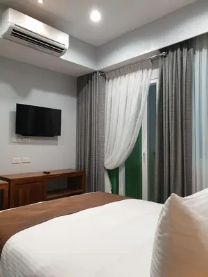 a hotel room with a bed and a flat screen tv at Leez Inn Makati in Manila