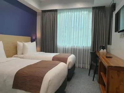 a hotel room with two beds and a desk at Leez Inn Makati in Manila