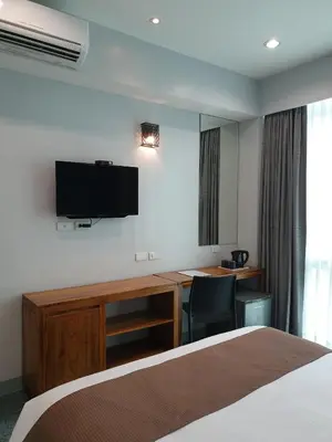 a hotel room with a bed and a desk and a tv at Leez Inn Makati in Manila