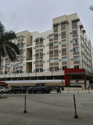 a large building with cars parked in a parking lot at Miranda's Suites by Fullerton in Puting Kahoy