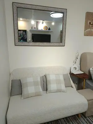 a couch in a living room with a mirror at Miranda's Suites by Fullerton in Puting Kahoy