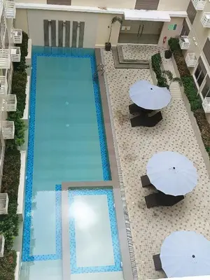an overhead view of a swimming pool with umbrellas and tables at Miranda's Suites by Fullerton in Puting Kahoy