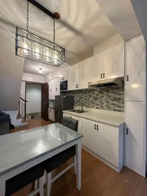a kitchen with white cabinets and a table in it at Newly Reneuvated Fully Furnished Condo Apartment in the Heart of Mandaluyong in Manila