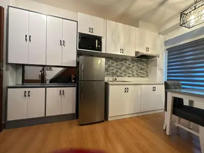 a kitchen with white cabinets and a stainless steel refrigerator at Newly Reneuvated Fully Furnished Condo Apartment in the Heart of Mandaluyong in Manila