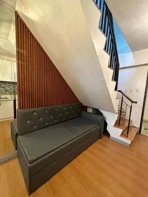 a black couch in a room with a staircase at Newly Reneuvated Fully Furnished Condo Apartment in the Heart of Mandaluyong in Manila