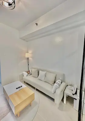 a white living room with a couch and a table at Cozy Beit 1125 in Metro Manila in Manila