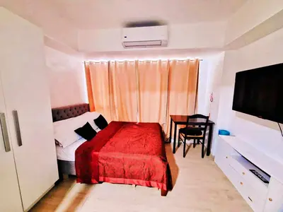 a bedroom with a bed with a red blanket and a table at Azure Urban Resort Residences Paranaque Near Airport and Mall in Manila