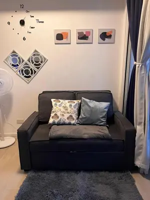 a couch in a living room with some pictures on the wall at Azure Urban Residences by Lyn in Manila