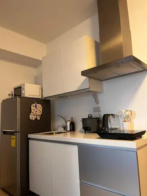 a kitchen with a black refrigerator and white cabinets at Azure Urban Residences by Lyn in Manila