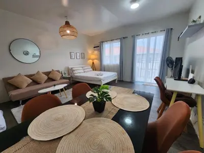 a living room with a couch and a table and chairs at The Little Abode Nuvali - Smart Studio Unit with Balcony & free pool access in Calamba