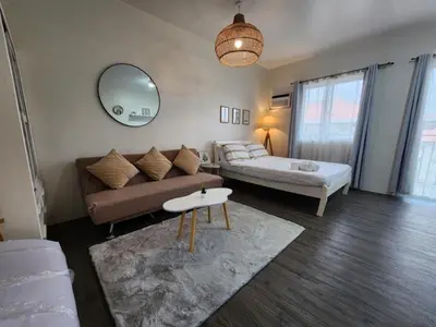 a living room with a couch and a bed and a mirror at The Little Abode Nuvali - Smart Studio Unit with Balcony & free pool access in Calamba