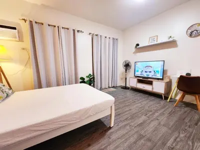 a bedroom with a bed and a flat screen tv at The Little Abode Nuvali - Smart Studio Unit with Balcony & free pool access in Calamba