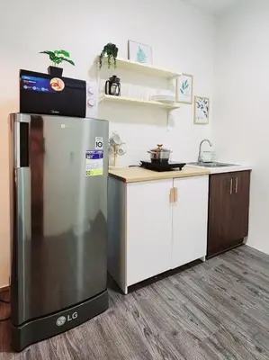 a kitchen with a stainless steel refrigerator and cabinets at The Little Abode Nuvali - Smart Studio Unit with Balcony & free pool access in Calamba