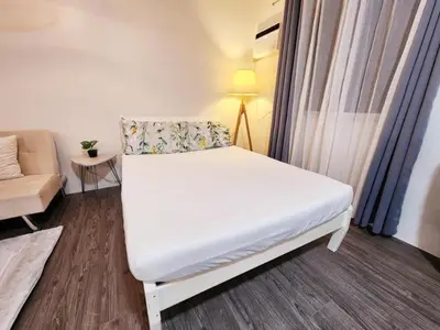 a small room with a white bed and a couch at The Little Abode Nuvali - Smart Studio Unit with Balcony & free pool access in Calamba