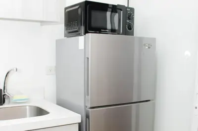 a microwave on top of a refrigerator in a kitchen at Stars & Sunsets Sky Views 1br Iguazu Tower in Manila