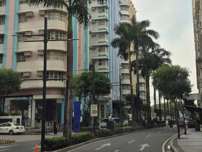 a city street with palm trees in front of a tall building at A&G Condotel at 101newport Near NAIA T3 in Manila
