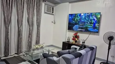 a living room with a couch and a tv on the wall at SMT Condo Hotel in Manila