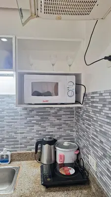 a microwave above a stove in a kitchen at Cozy Staycation in Manila