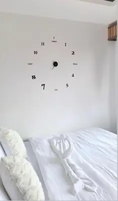 a white bed with a clock on the wall at Cozy Staycation in Manila
