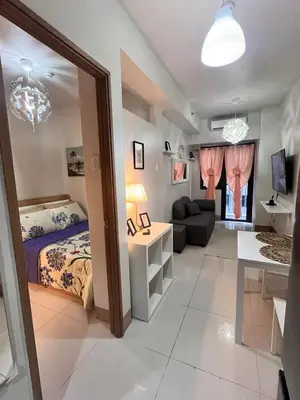 a bedroom with a bed and a living room at Sofia's place shore 3 tower 2 in Manila
