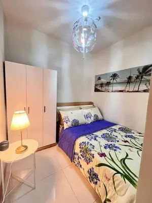 a bedroom with a bed and a table and a lamp at Sofia's place shore 3 tower 2 in Manila