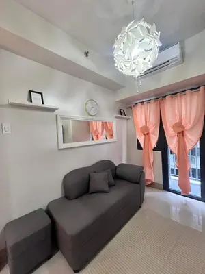 a living room with a couch and a chandelier at Sofia's place shore 3 tower 2 in Manila