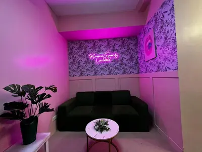 a living room with a couch and a neon sign at Kasara Serenity Condotel in Manila