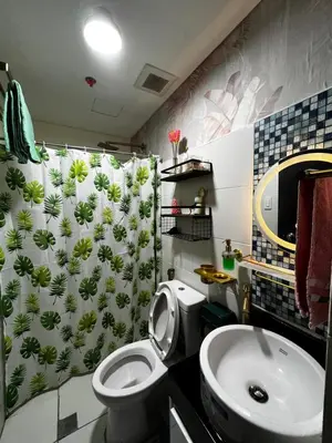 a bathroom with a toilet and a sink and a shower curtain at Kasara Serenity Condotel in Manila