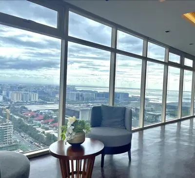 a living room with a chair and a table and windows at Cozy Nook at Coast Residences in Manila