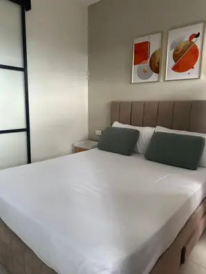 a bedroom with a large white bed with two green pillows at Cozy Nook at Coast Residences in Manila