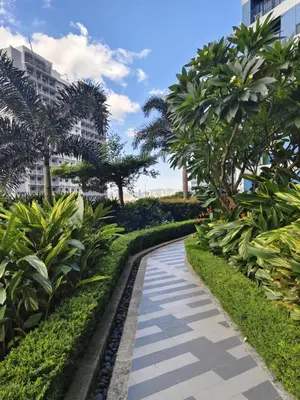 a walkway through a park with palm trees at Air Residences Suite by Christine Suites PH in Manila