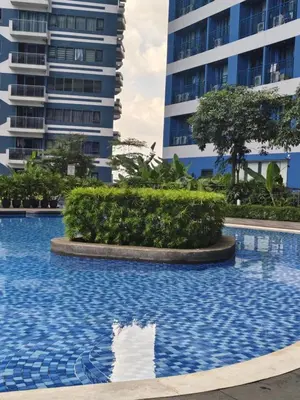 a swimming pool in front of a tall building at Air Residences Suite by Christine Suites PH in Manila